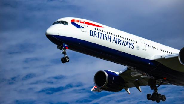 British-Airways-Flugzeug im Flug mit ausgefahrener Fahrwerksklappe.