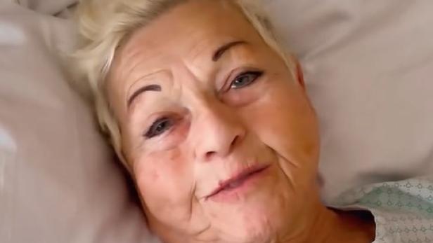 Jazz Gitti liegt im Krankenhausbett im OP-Hemd und blickt in die Kamera.