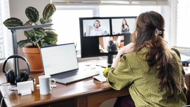 Frau im Homeoffice vor Laptop und Monitor bei Videokonferenz.