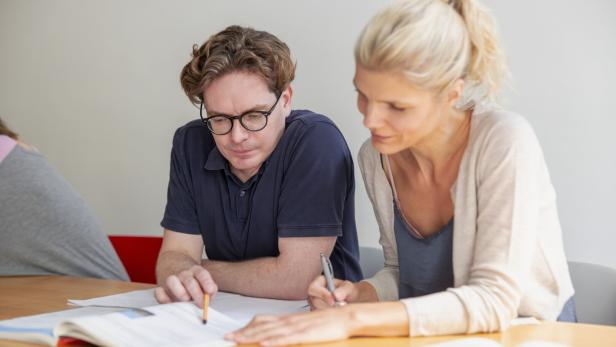 Two students learning foreign language in adult education classroom