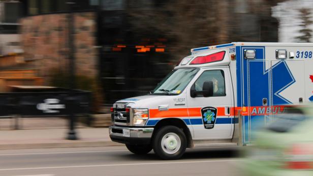 Weiß-blau-roter Krankenwagen, der auf der Straße unterwegs ist