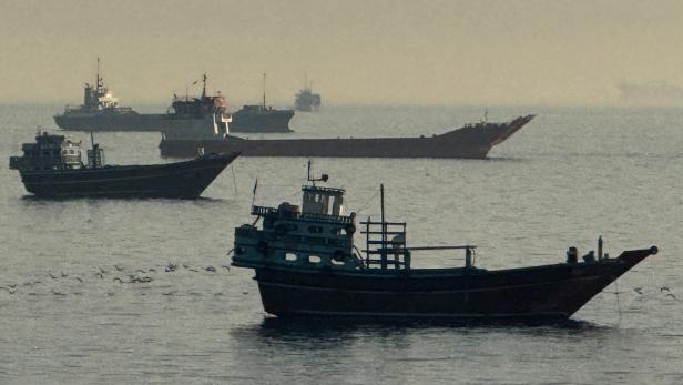 Mehrere Fracht- und Fischereischiffe liegen bei diesigem Wetter auf dem ruhigen Meer.