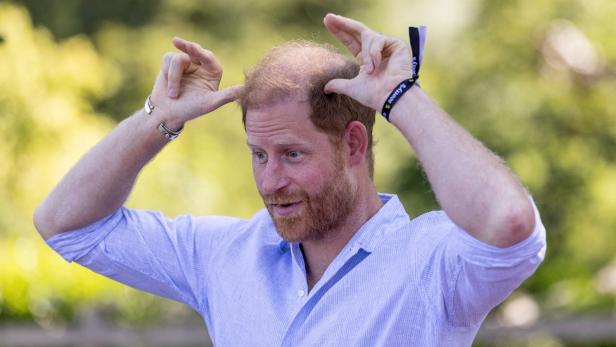 Prinz Harry macht mit seinen Händen Hasenohren über seinem Kopf.