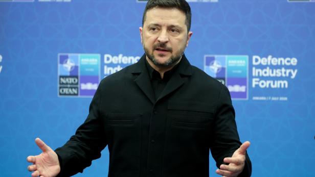 Wolodymyr Selenskyj spricht vor einem blauen Hintergrund mit Logos des NATO Defence Industry Forum.