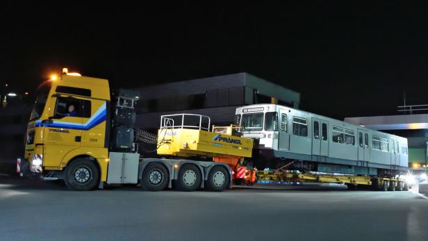 Ein gelber Schwertransporter der Firma Prangl transportiert einen U-Bahn-Waggon bei Nacht.