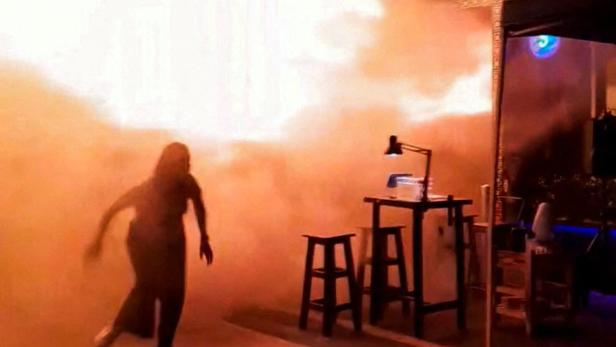 A person runs as flames rise at a pub in Bangkok