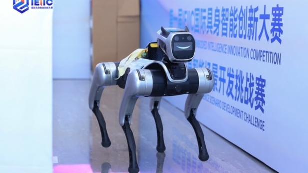 Vierbeiniger Roboterhund auf glänzendem Boden vor einer Wand mit chinesischer Beschriftung.