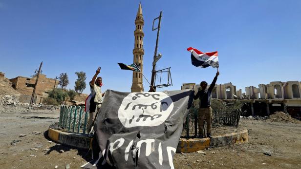 FILE PHOTO: Shi'ite Popular Mobilization Forces (PMF) members hold an Islamic State flag, which they pulled down, during the war between Iraqi army and Shi'ite Popular Mobilization Forces (PMF) against the Islamic State militants in Tal Afar
