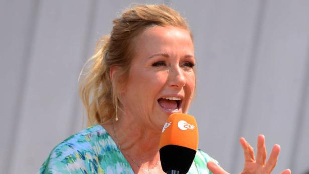 Andrea Kiewel spricht beim ZDF-„Fernsehgarten“ mit Mikrofon in der Hand.