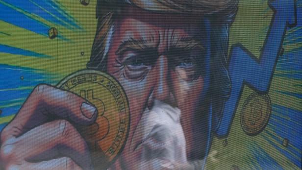 FILE PHOTO: An illustration outside a store in Hong Kong shows US President Donald Trump holding bitcoin