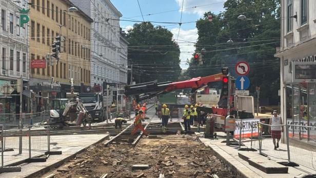 Straßenbahngleise werden von Arbeitern und Baufahrzeugen auf einer gesperrten Stadtstraße erneuert.