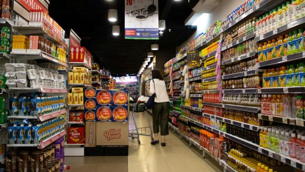 Frau mit Einkaufswagen geht durch Supermarkt