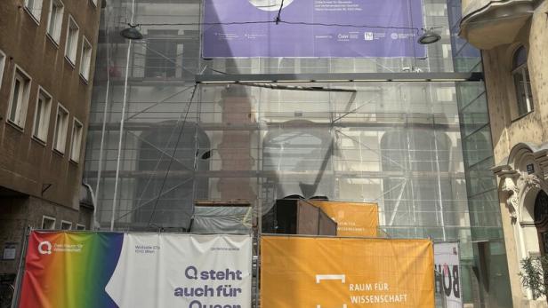 Gerüst um ein Gebäudeteil mit großen Wissenschafts-Bannern, darunter bunte und orange Werbetafeln.