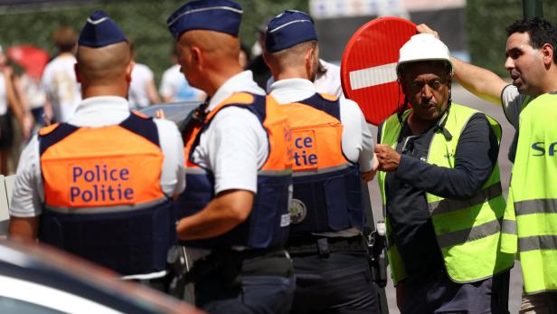 Polizisten und Bauarbeiter besprechen sich vor einem Stoppschild.