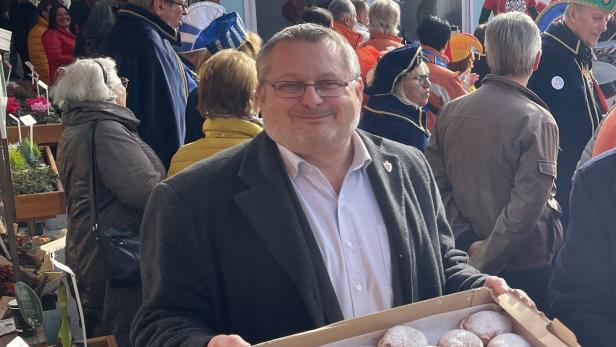 Andreas Kutheil auf einem Fest mit Krapfen in der Hand.