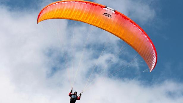 Mann fliegt mit Gleitschirm durch den Himmel