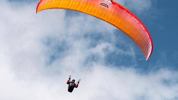 Mann fliegt mit Gleitschirm durch den Himmel