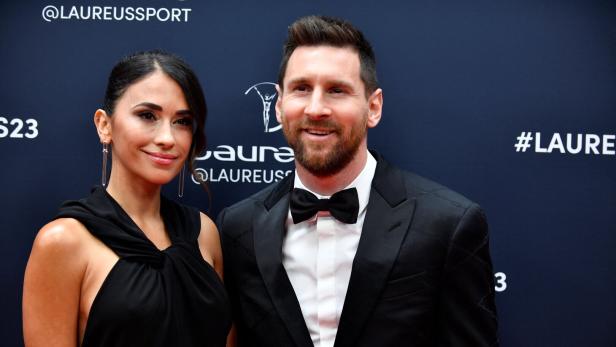 Lionel Messi und seine Frau Antonela Roccuzzo posieren gemeinsam bei der Laureus World Sports Awards Verleihung vor einem dunklen Hintergrund.