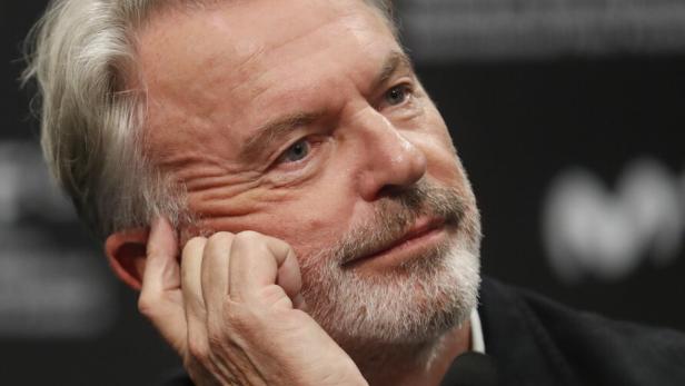 Der Schauspieler Sam Neill stützt nachdenklich seinen Kopf auf die Hand.
