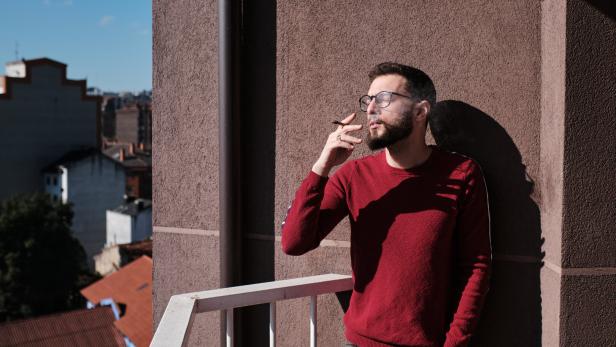 Mann raucht am Balkon