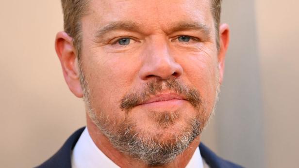 Nahaufnahme des Schauspielers Matt Damon mit kurzem Bart vor einem neutralen Hintergrund.