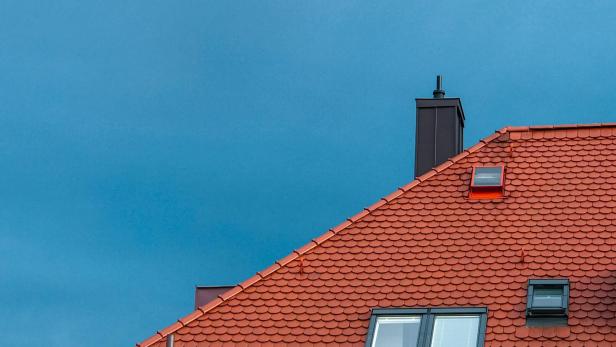Rotes Dach eines Hauses mit einem Fenster und Schornstein