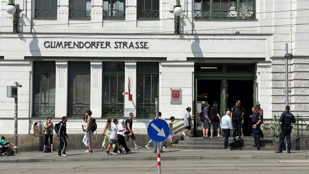 Menschen gehen vor dem historischen Gebäude der U-Bahn-Station Gumpendorfer Straße in Wien ein und aus, während Polizisten vor dem Eingang stehen.
