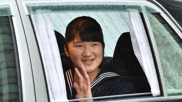 Prinzessin Aiko von Japan winkt lächelnd aus dem Fenster eines Autos.