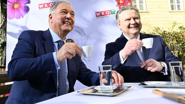 Walter Ruck und Michael Ludwig im Anzug trinken im Freien Espresso an einem Tisch vor einem WKO-Hintergrund.