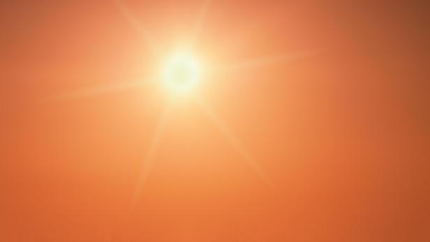 The sun shining brightly in a clear orange sky