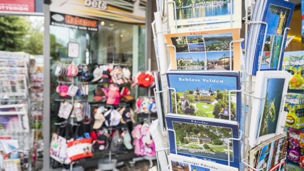 Postkartenständer vor einem Souvenirshop mit Ansichten vom Wörthersee und Schloss Velden.