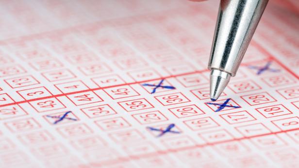 Close-up of a pen marking numbers on a lottery ticket.