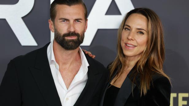 Melanie Chisholm und Chris Dingwall posieren vor einem dunklen Event-Hintergrund.