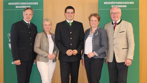 Fünf Personen in Tracht stehen vor Bannern des Niederösterreichischen Bauernbunds.
