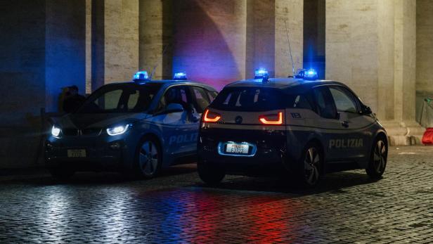 Zwei Polizeiautos mit Blaulicht auf nassem Pflaster bei Nacht.