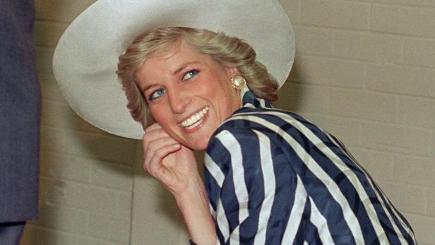 Prinzessin Diana lächelt in einem blau-weiß gestreiften Kostüm und einem passenden weißen Hut.