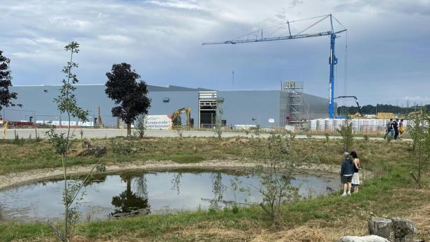 Zwei Personen an einem kleinen Teich vor der Baustelle des neuen Google-Rechenzentrums in Kronstorf.