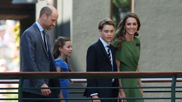 Prinz William, Prinzessin Kate, Prinz George und Prinzessin Charlotte gehen gemeinsam an einem Geländer entlang.