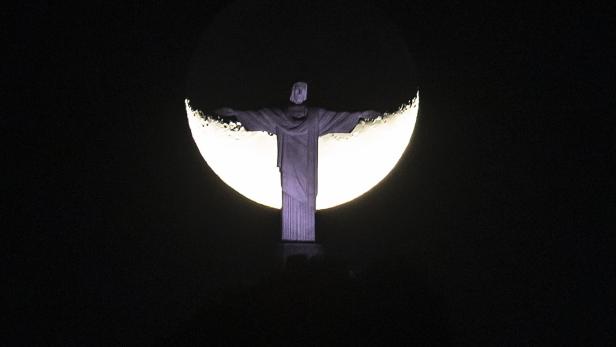 Moon rises behind Christ the Redeemer statue in Rio de Janeiro