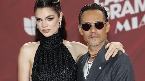 Nadia Ferreira und Marc Anthony posieren gemeinsam vor einem roten Hintergrund bei den Latin Grammys in Miami.