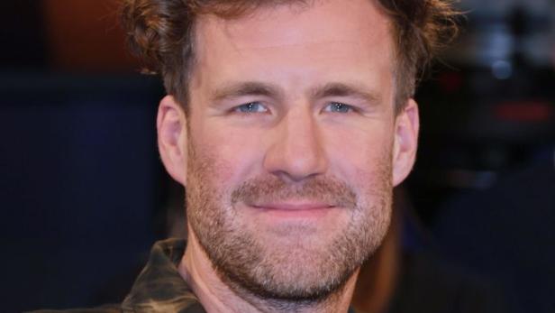 Luke Mockridge lächelt in die Kamera bei einem öffentlichen Auftritt.