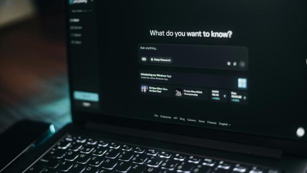Laptop mit geöffneter KI-Chatoberfläche auf dunklem Bildschirm.