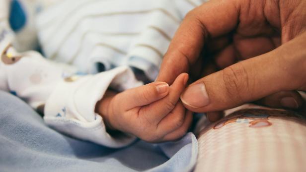 Person, die den Zeigefinger des Babys hält
