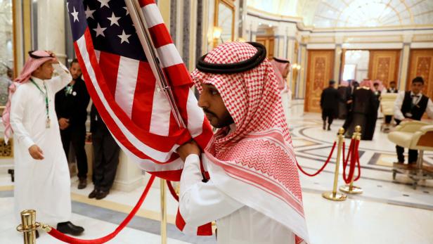 FILE PHOTO: A worker carries a U.S. flag into a meeting room ahead of U.S. President Donald Trump's meeting with Gulf Cooperation Council leaders in Riyadh