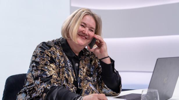Anna Hergan telefoniert lächelnd am Schreibtisch.