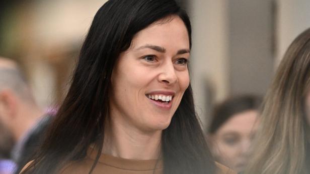 Eine lächelnde Ana Ivanovic mit langem, dunklem Haar trägt ein braunes Oberteil.