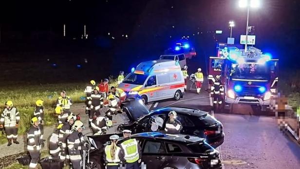Rettungskräfte arbeiten nachts an einem schweren Verkehrsunfall mit zwei beschädigten Autos und mehreren Einsatzfahrzeugen.