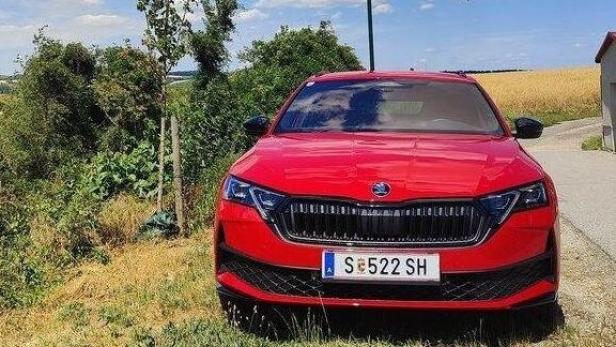 Ein roter Skoda steht an einer ländlichen Straße unter einem sonnigen, blauem Himmel mit weißen Wolken.