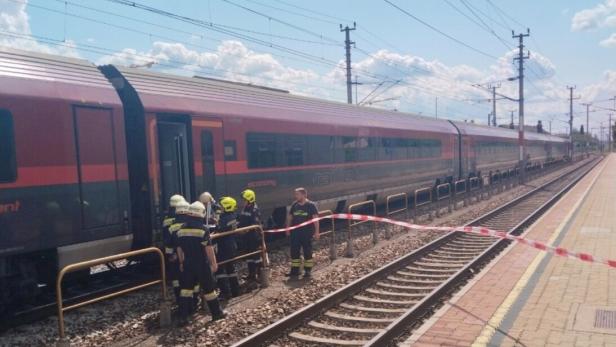 Feuerwehrleute sichern einen Zug am Bahnsteig hinter Absperrband.