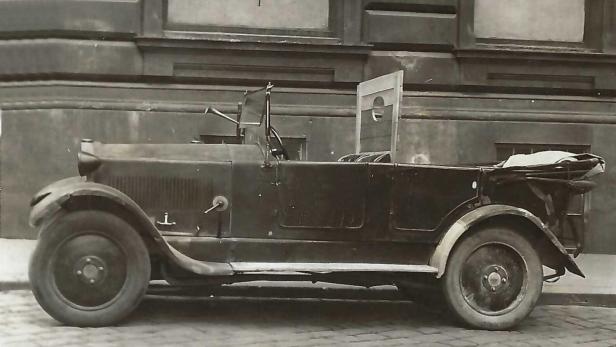 Altes schwarzes Cabrio vor einem Gebäude geparkt.